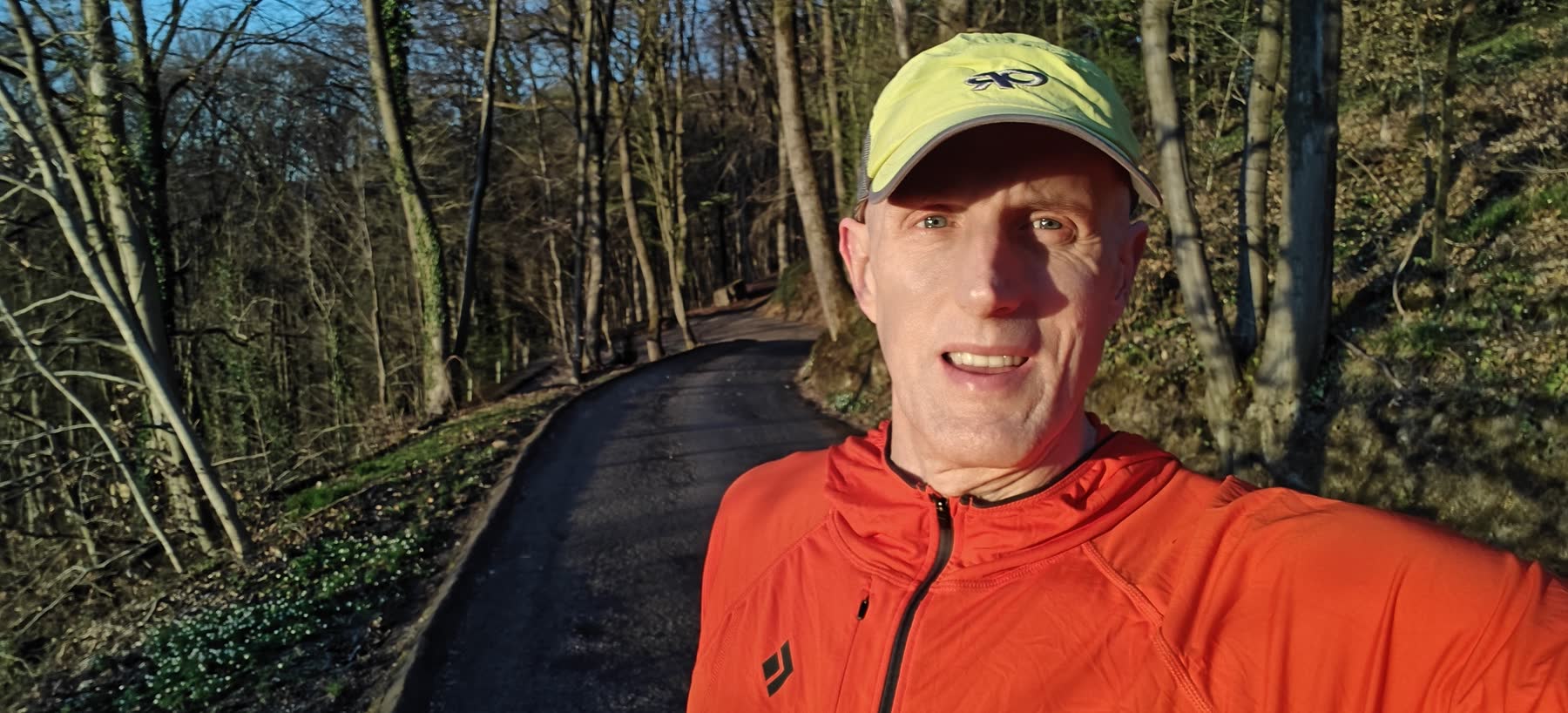Runner in an orange jacket on a wooded long run